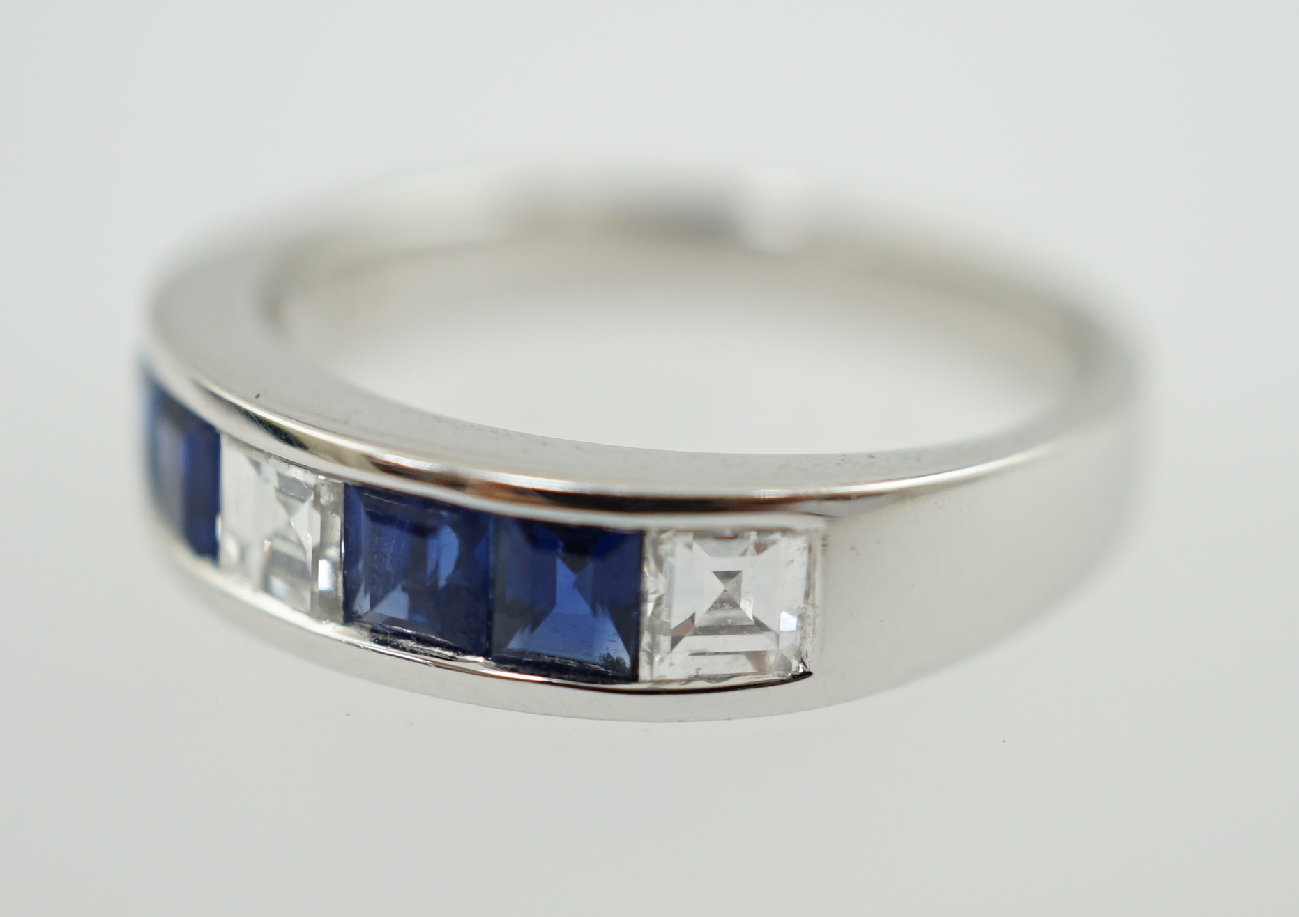 A modern 14k white gold, three stone diamond and four stone sapphire half hoop ring
